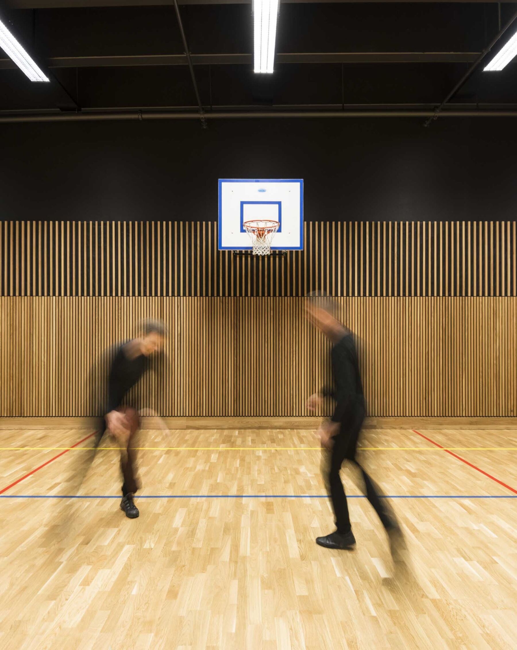 To personer spiller basketball i en stor gymsal. Foto.