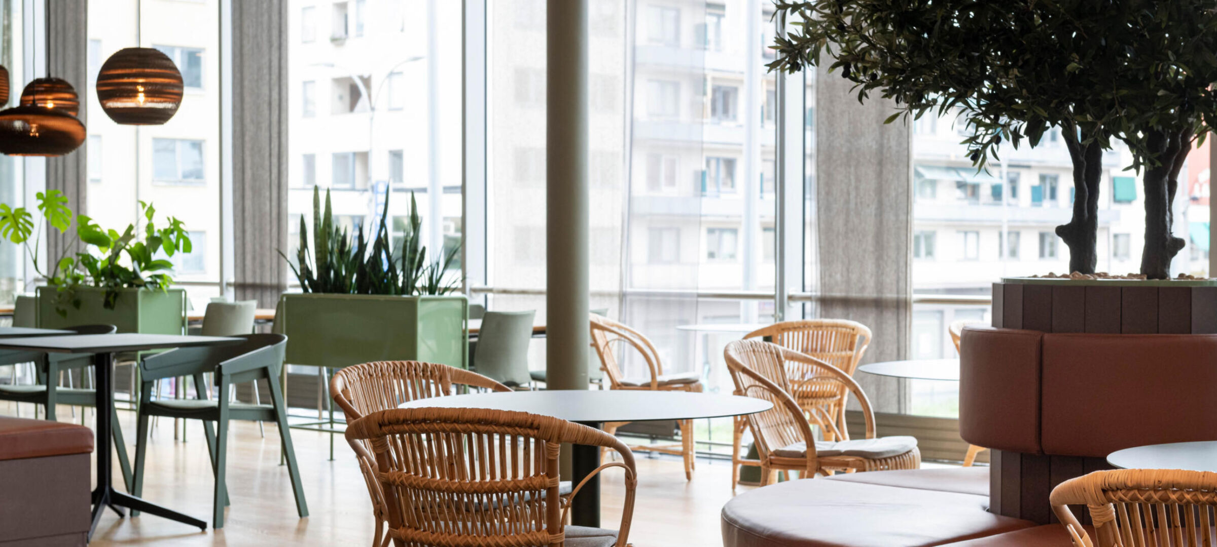 Kantine bestående av ulike sitegrupper. Stoler, bord, plantekasser og planter. Foto.