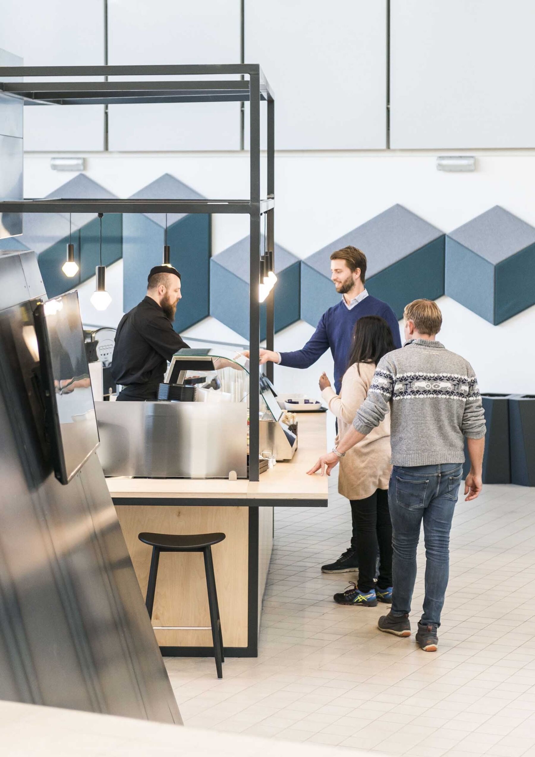 Mennesker står i kø for å betale i kantine. Foto.