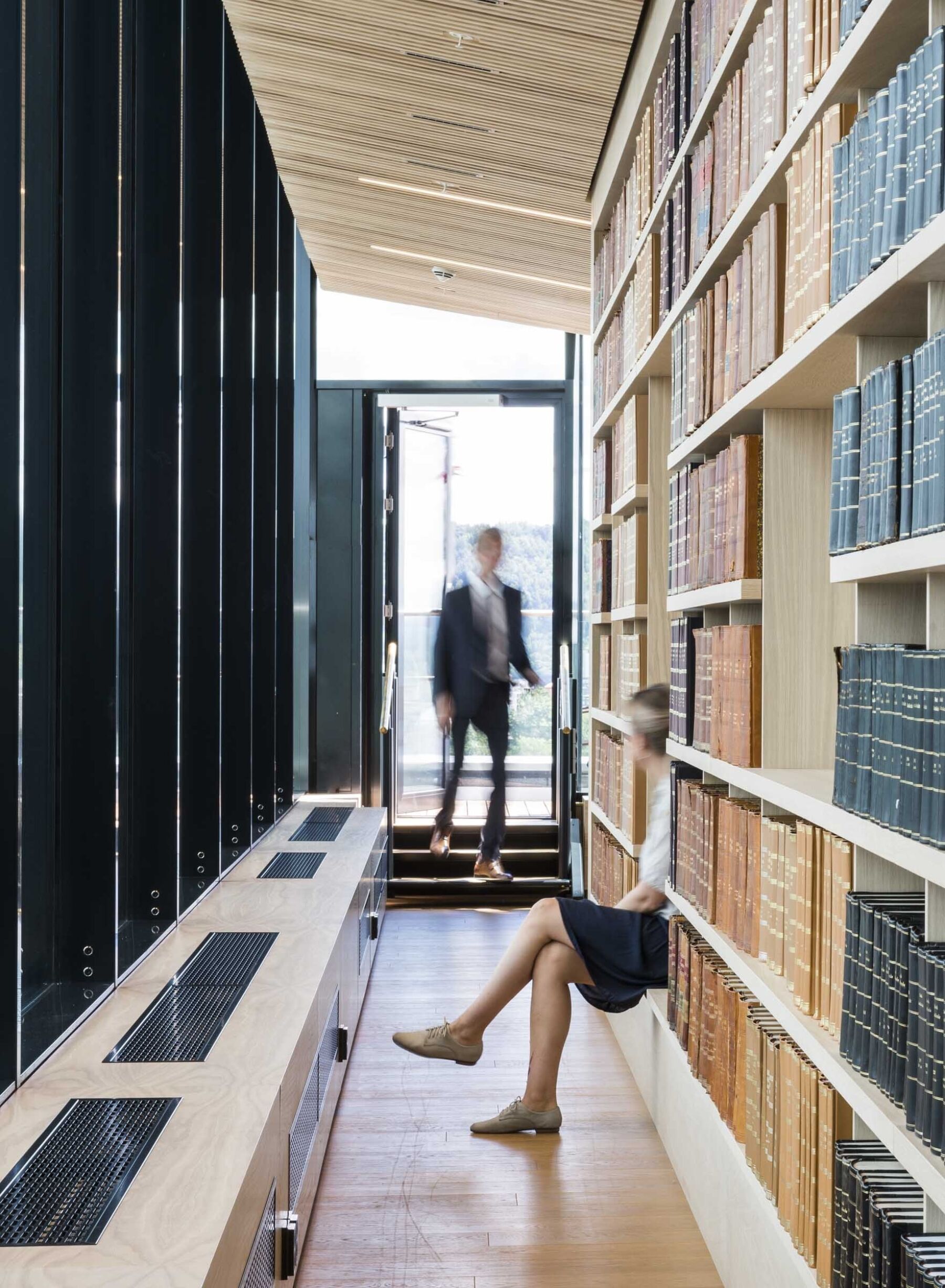 Kvinner og mann beveger seg i bibliotek. Foto.